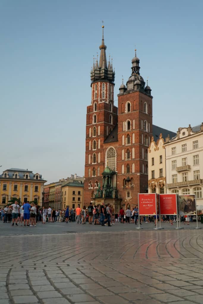 Eine rote Kirche mit zwei Türmen an einem Platz.