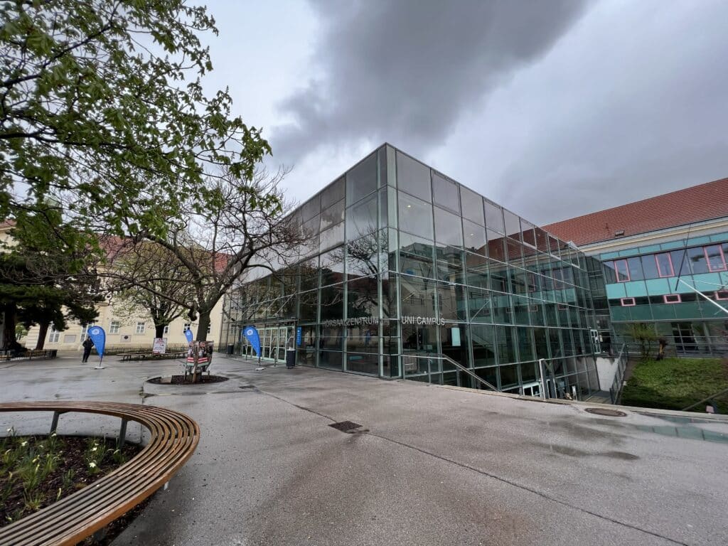 Foto des Außenbereichs vor einem kubischen Gebäude mit Glasfassade